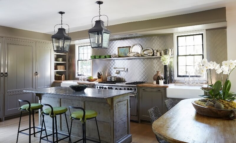 The patina of the wooden table and kitchen island are artistically juxtaposed by the striking stainless steel wall backsplash. melanie pounds