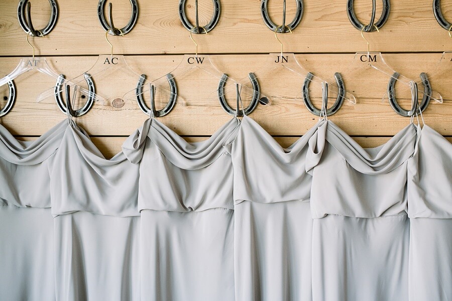 Matching silk dresses contrast beautifully with the venue's horseshoe hooks, a nod to the polo center. We also adore the cleverly initialed hangers. bridesmaid dresses on horseshoe hooks