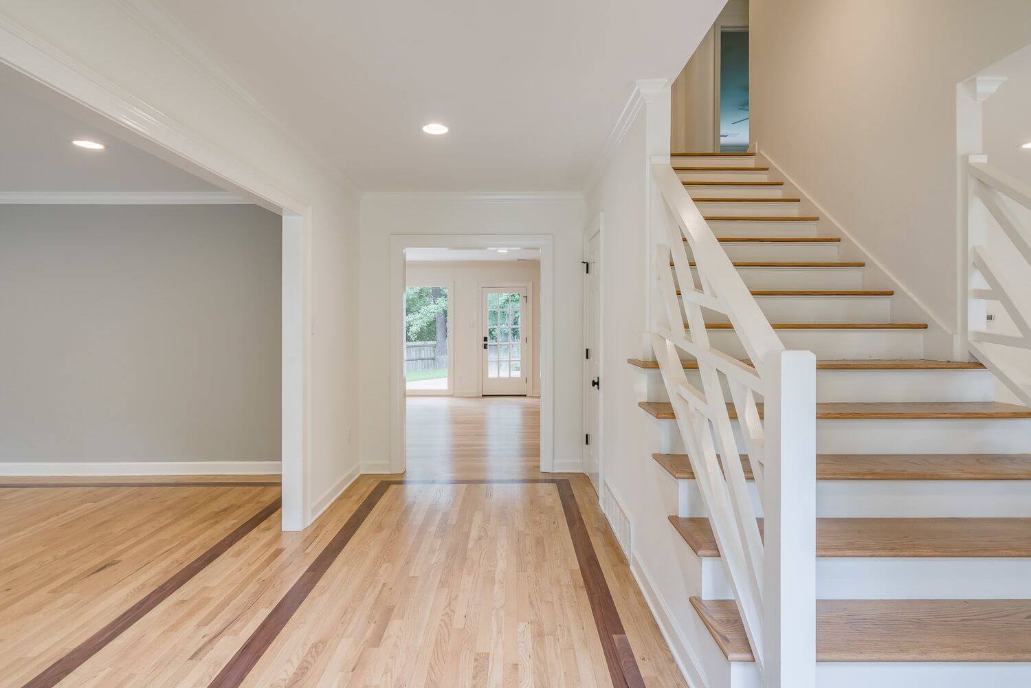 The exterior sets the tone for what you find inside. In an effort to make the entryway feel open, they removed a wall separating the staircase and the dining room. Open entryway by R. Co Construction