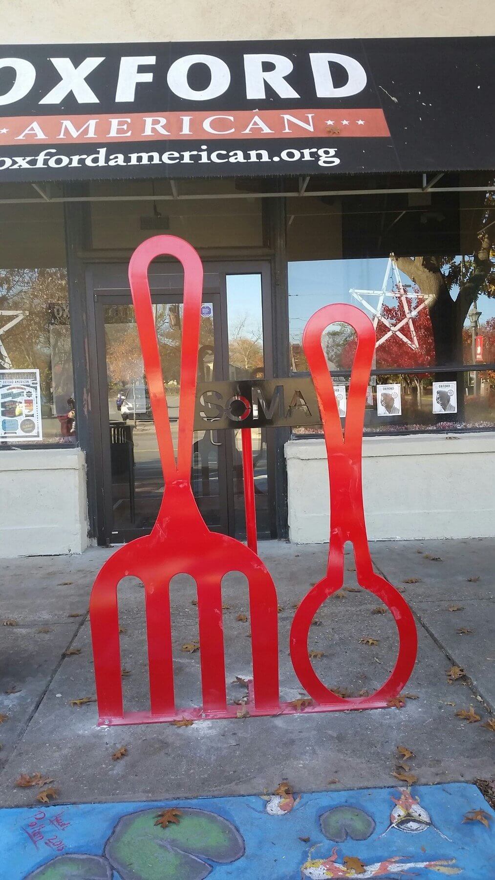sculpture of a fork and spoon on the sidewalk in front of Oxford American