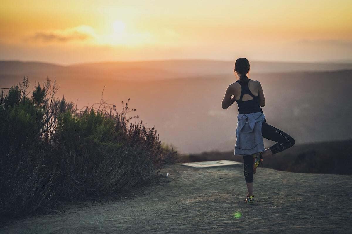 Woman doing sunrise yoga on mountaintop