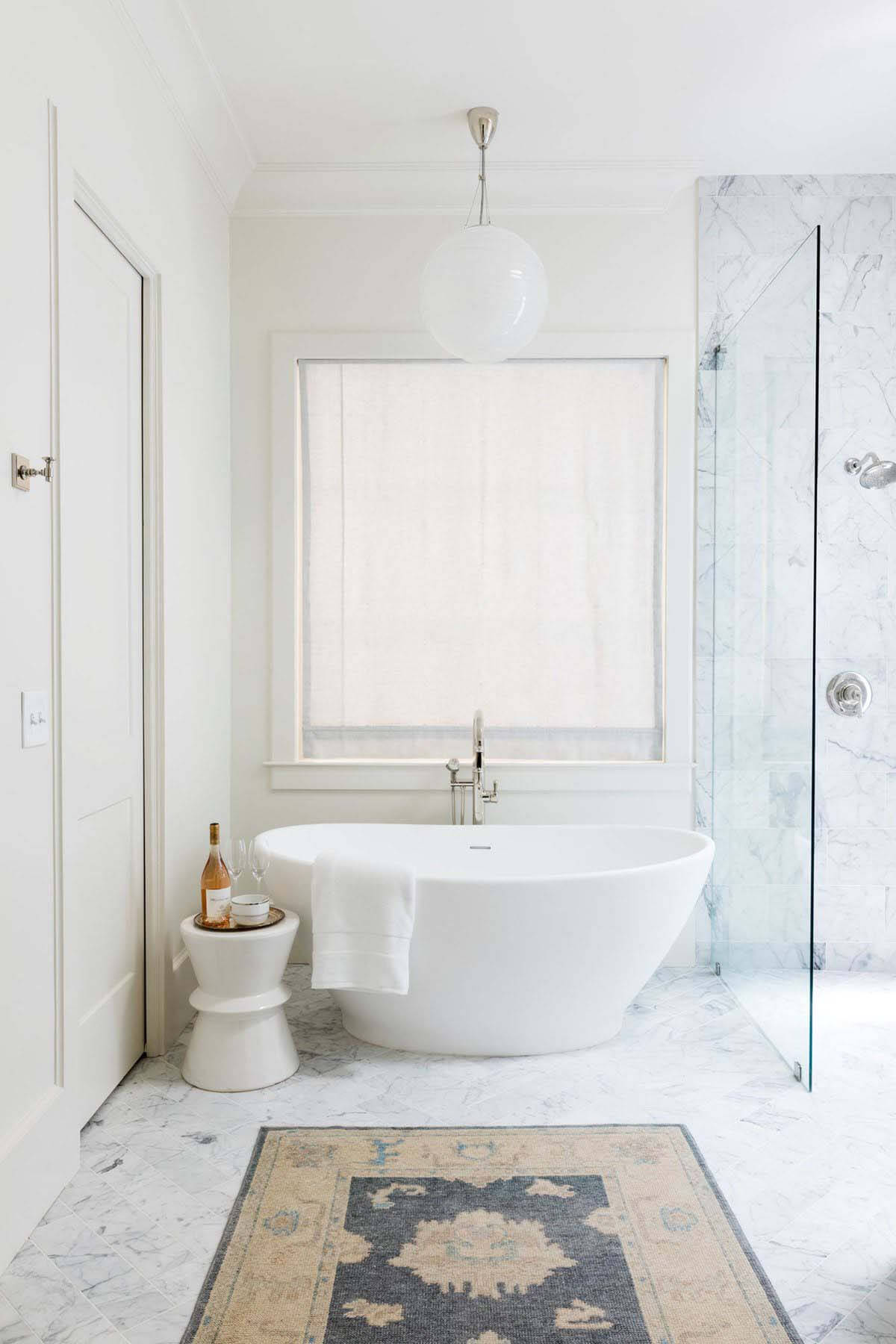 A vintage rug adds history and texture to the master bath. All-white master bathroom with vintage rug in Orr home