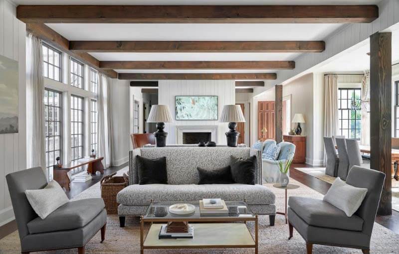 "I’ve never done back-to-back sofas before, but in that big front room, the main space is so long," says Designer Rachel Halvorson of the wide-open living room. "I was able to divide it up into two sitting areas — one that’s a little more focused and closer to the fireplace and TV, and another that faces back toward the kitchen. I love the furniture layout and how that worked out." She used an earthy botanical print from Perennials Fabrics along with deep green mohair pillows, to contrast the stunning beams. Interior Pfeffer Torode living room with back-to-back sofas