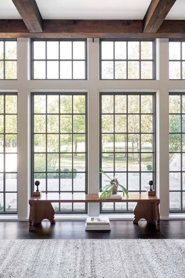 Originally, the windows were intended to remain the same color as the walls so as to maintain a lighter, brighter feel. Once the windows were framed up, however, the on-site decision was made to accentuate them with dark trim, creating another layer of texture so they wouldn't disappear. Opting for simplicity, Rachel chose this bench from Holland MacRae in Atlanta, which serves as a functional sculptural piece. Floor-to-ceiling window with charming wood bench.