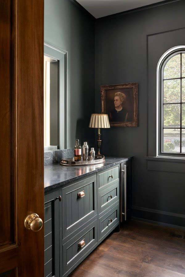 Farrow & Ball's Studio Green was used for both the cabinets and walls in this burler's pantry, inspired by the rich tones in a portrait of the homeowner's grandmother. "We wanted it to feel like a little jewelry box, where it's all the same color," says Rachel. Butler's pantry with portrait of the homeowner's grandmother