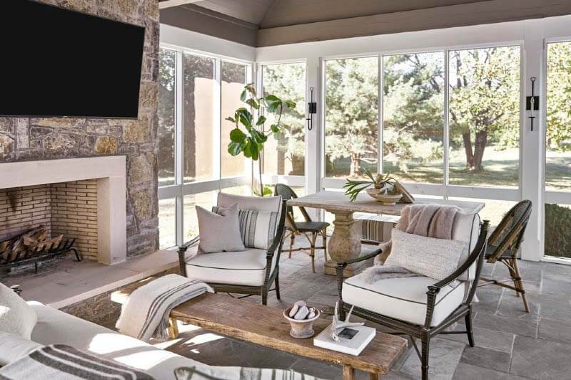 Of the screened porch, Rachel tells us, "I wanted to design it so it would have space for sitting and dining. The sofa and loveseat are these iron-framed pieces from Century Furniture, with natural upholstery. There's also a big stone table in the back" — perfect for family and guests alike. Screened porch of Pfeffer Torode-designed home
