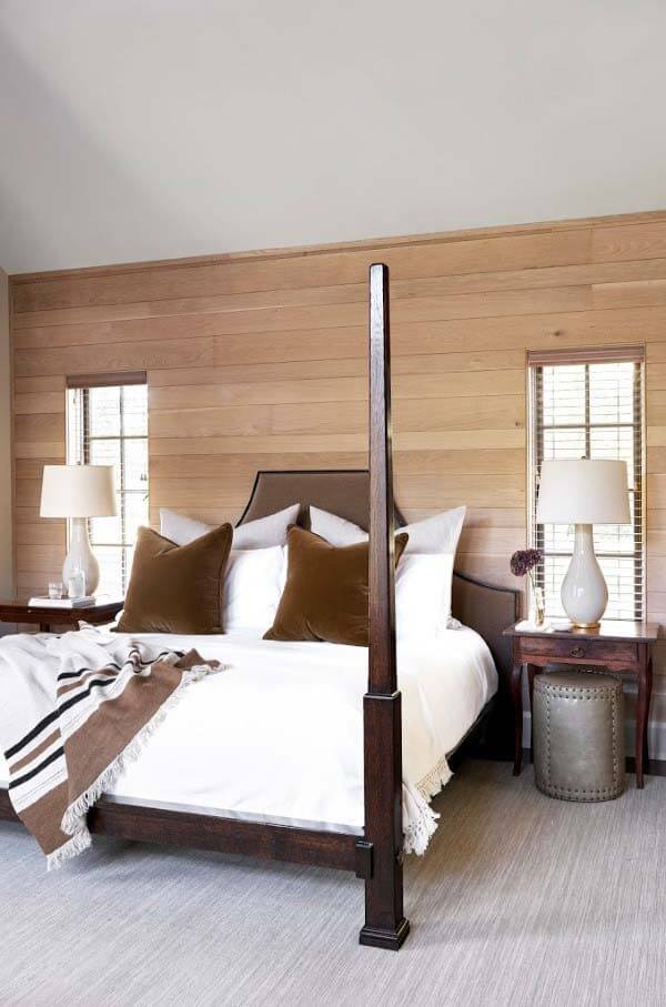 The master bedroom ceiling reaches a full two stories on one side and dips down low on the other, giving way to an interesting design challenge. This unique bed by Bobby McAlpine, found through Holland MacRae, looks as though it was made with this exact room in mind! Master bed in front of wood focal wall at Forest Hills historic home