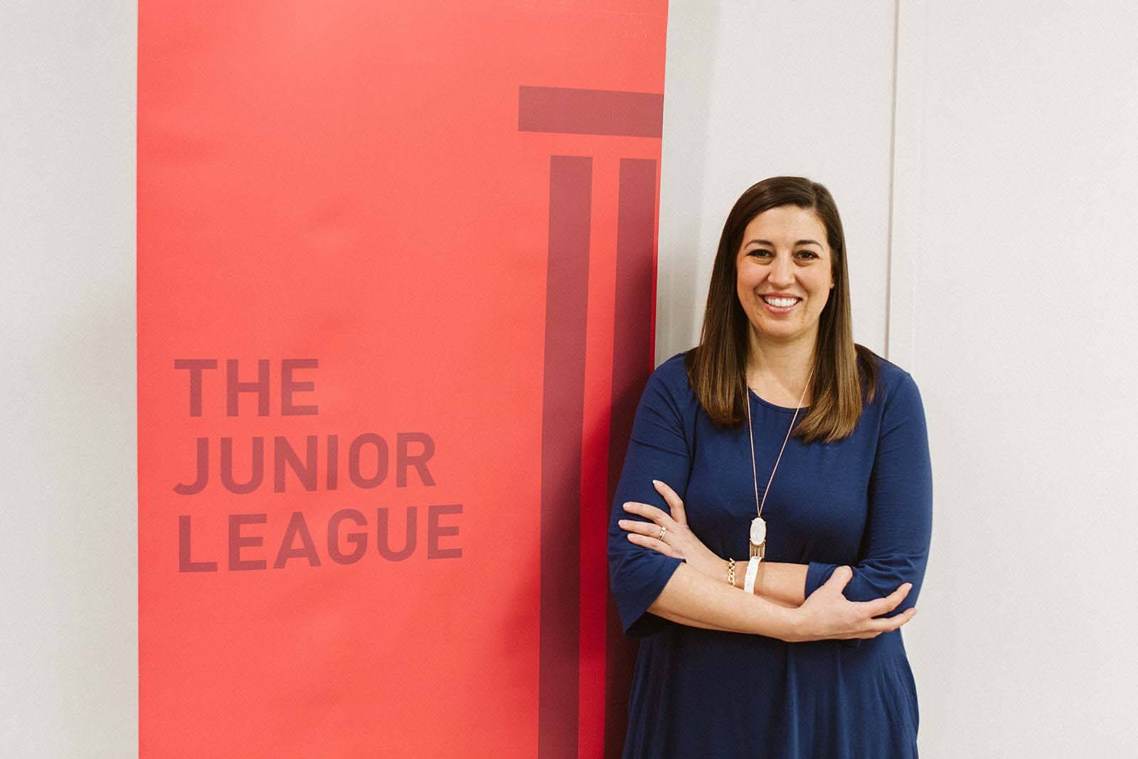 After recognizing JLL's need for leadership, Jessica stepped up to serve as president. She wanted to give back to the organization that has given so much to her. Jesica Dunleavy posing near red JLL banner