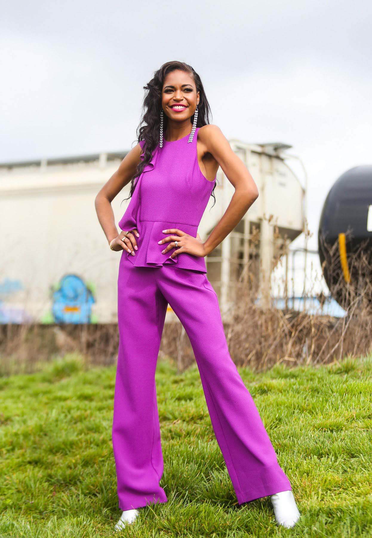 Model in violet pantsuit, in front of train