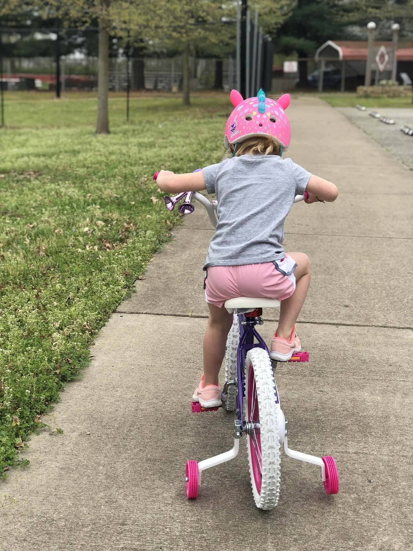 Marlowe learning to ride a bike with training wheels during quarantine home economics