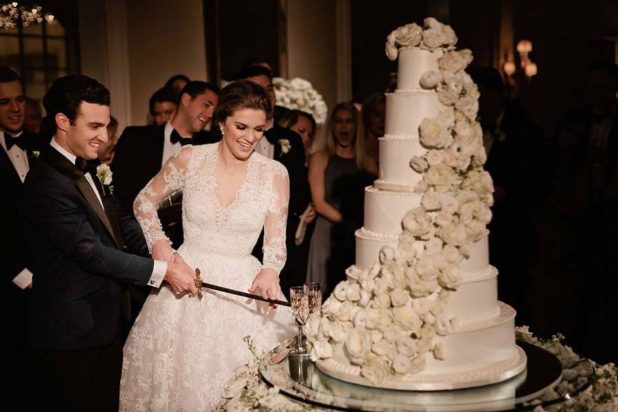 Cutting the cake with the family sword at a winter wonderland wedding | Photographer: Kristyn Hogan