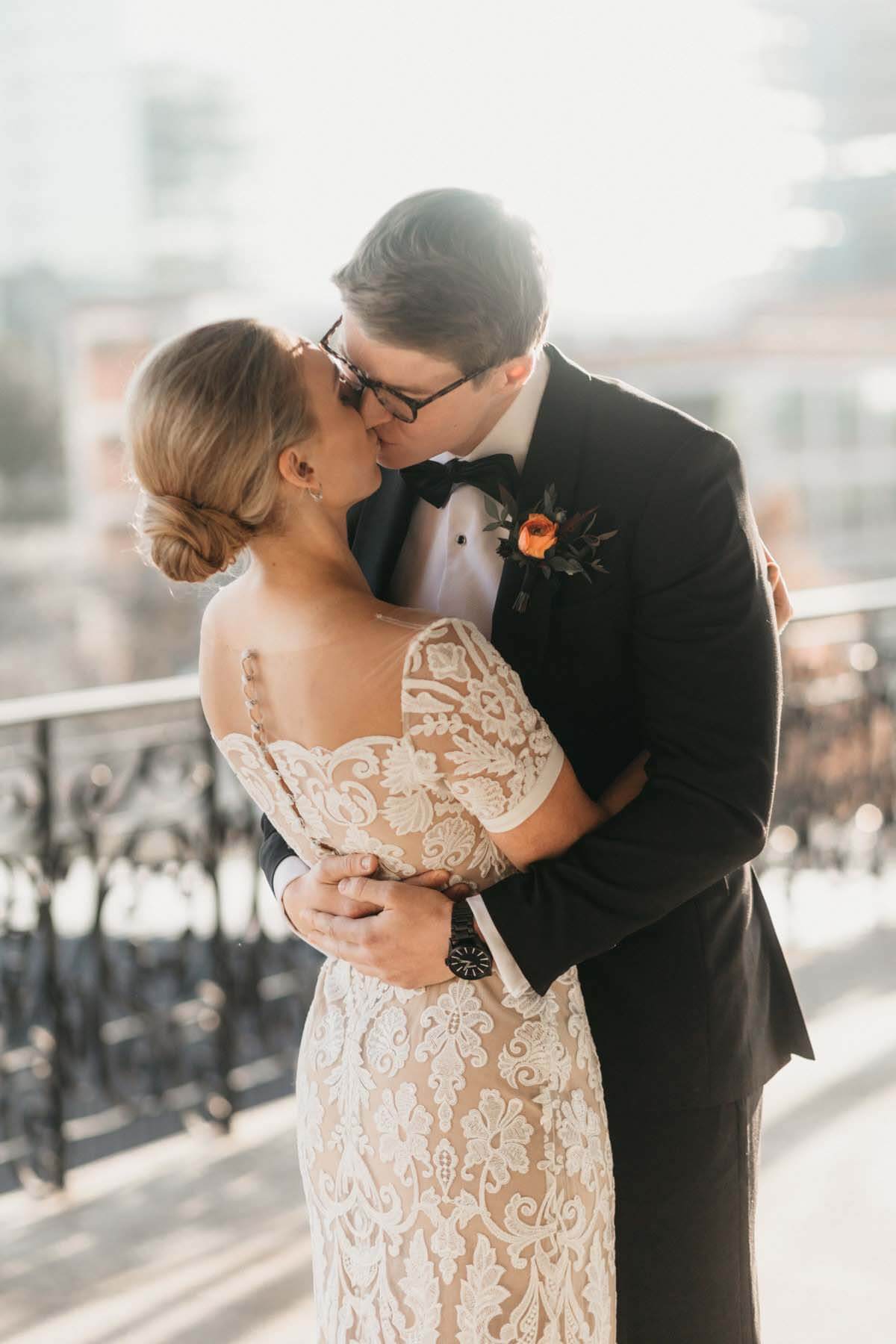 Bride and groom kissing on balcony before their autumn wedding