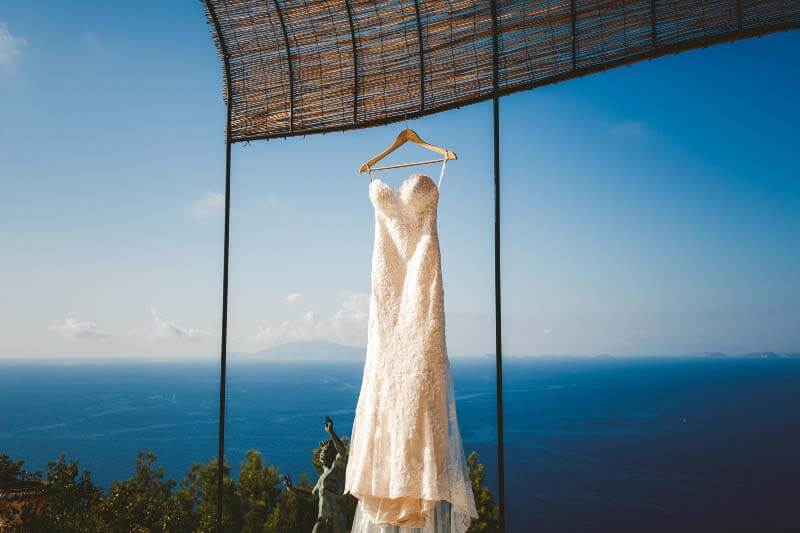 wedding dress hanging up at villa, overlooking ocean