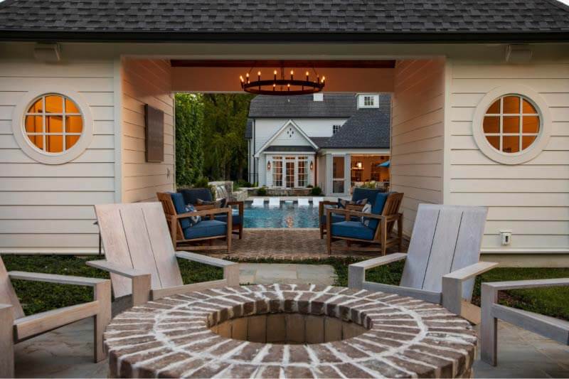 "The most unique feature of this project to me is the tucked-away fire pit area," says Van. "Sitting there, you can look back through the pool cabana to this whole village of moments — from the pool to the side terrace to the circular spa and lantern-like screened porch addition." Image: Chad Driver, Driver Productions Fire pit in font of outdoor lounge area, with pool in the background