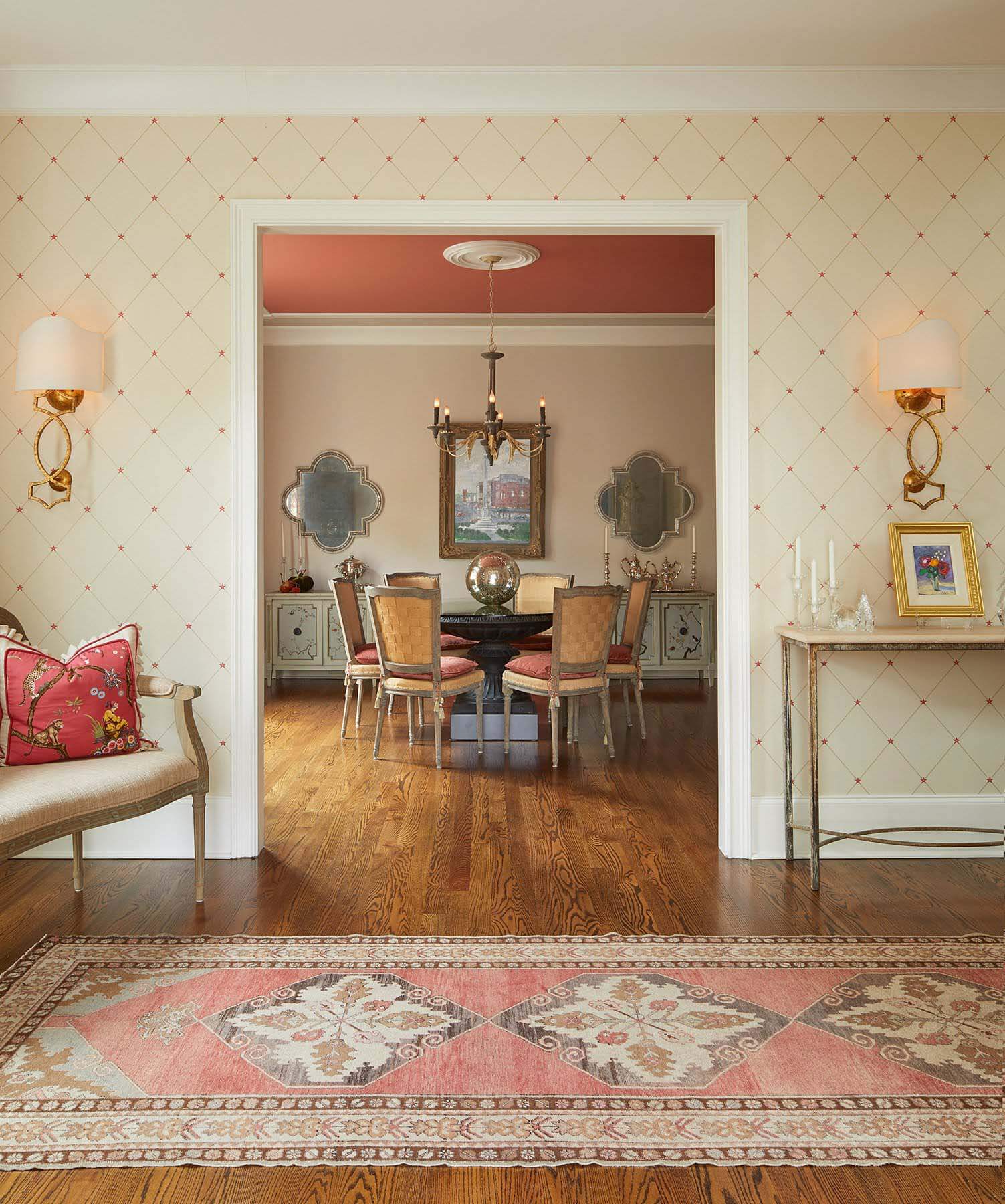 Though the rooms she was working with may not have been overly spacious, JoAnne Haynes, of J. Haynes Interiors, sought to give the dining room and entryway an open, airy feel. Introducing a coral color scheme, she chose a wall covering that boasts tiny coral stars, then picked up the color in pillow fabrics and even the dining room ceiling. Image: Gieves Anderson Inspired room and entryway by J. Haynes Interiors