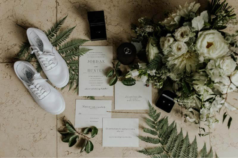 Jordan and Hunter's stunning invitations feature Val Cole Calligraphy. Here, the suite is surrounded by the bride's bouquet and shoes, as well as all of her accompanying wedding day jewelry. Invitation suite with bride's shoes and bouquet
