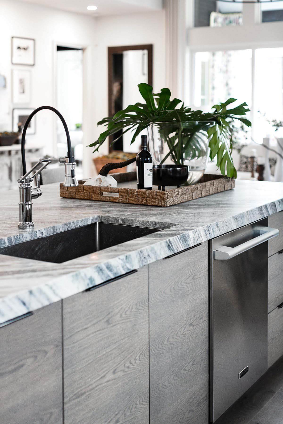 Again from MSI Surfaces, the kitchen's Fantasy Brown marble waterfall island complements the space's earthy tones and dark-colored hardware. Fantasy Brown marble waterfall island by MSI Surface