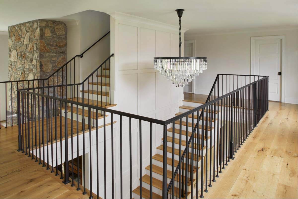 Rarely do we celebrate the stairs as a favorite feature in the home, but the juxtaposition of the chandelier, railings, moldings and stone fireplace is undeniably beautiful. From this corner of the house, the combination of styles and textures is on full display. Staircase in renovated ranch home