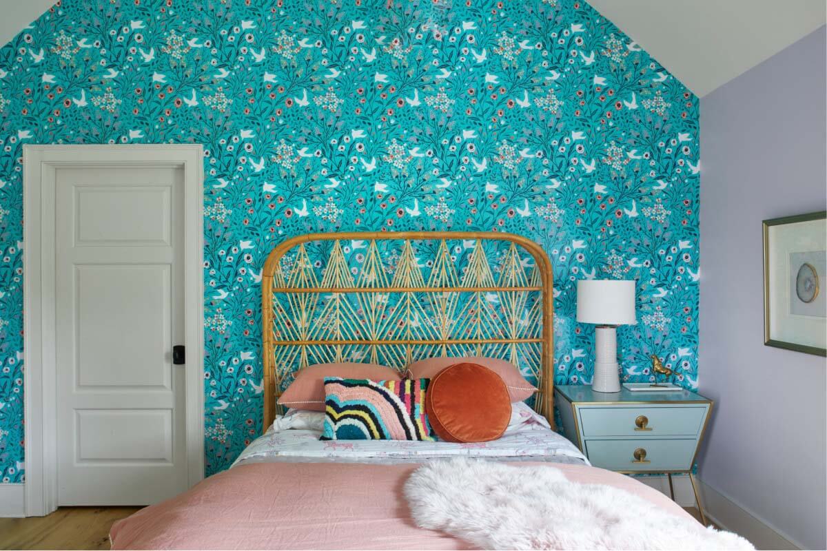 The oldest daughter gave Sara input for her room design, resulting in a colorful and cool space that reflects her personality. Young girl's bedroom with patterned wallpaper and pink bed