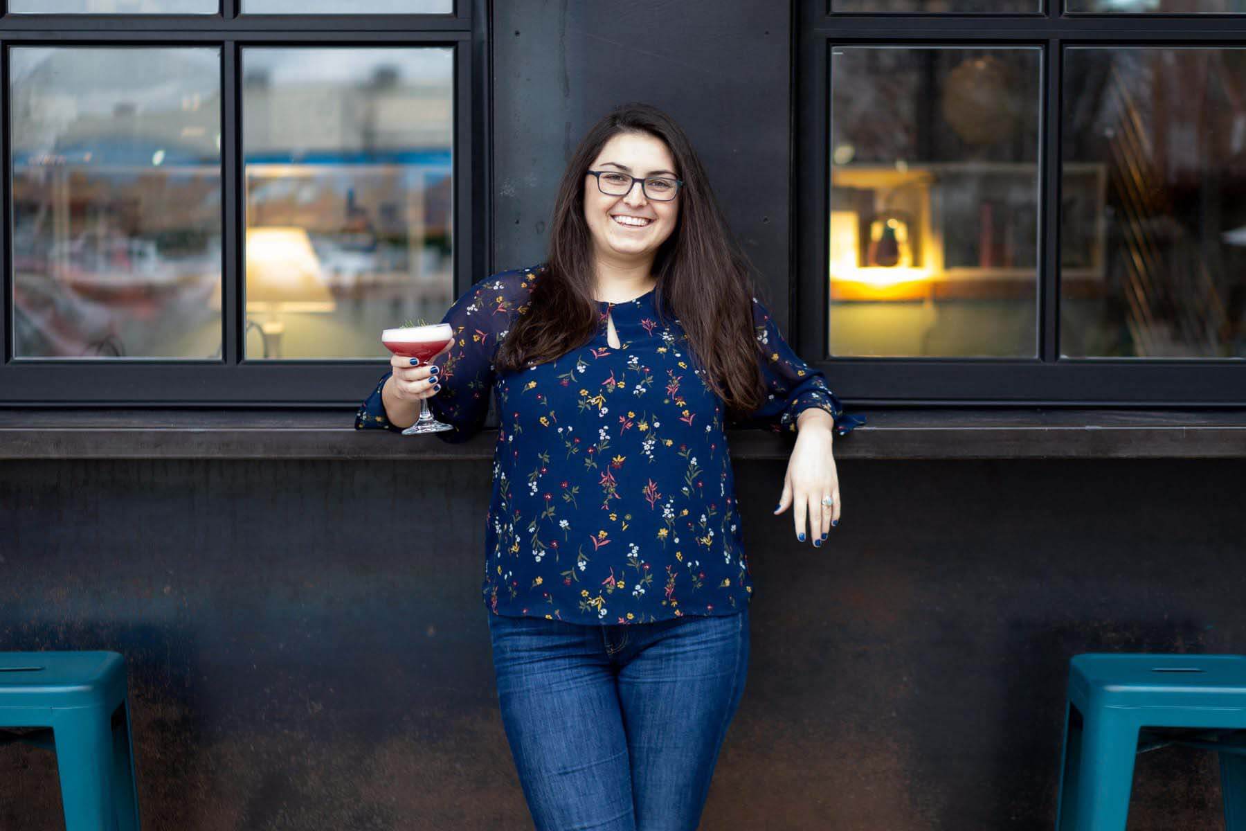 Rylie credits her team at The Lumbar for helping her juggle her time between school, research and the bar: "They are 'ride or die,' and we all love each other. They’re willing to do whatever it takes to move things forward. That’s been the biggest help in juggling." Rylie Hightower posing with a cocktail