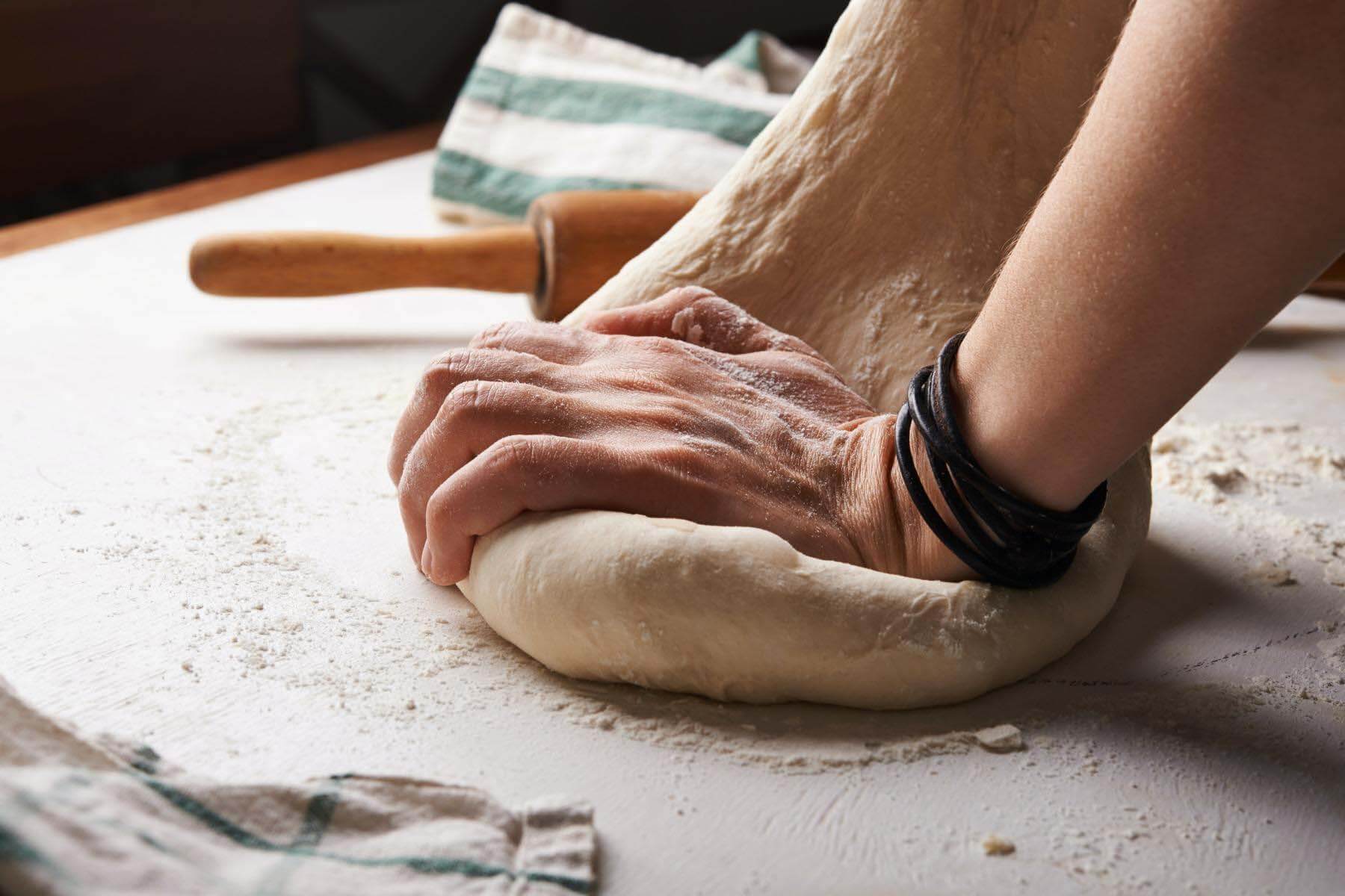 Take-home pizza kit, $15 to $25, from Gino's East Someone rolling out pizza dough for at-home cooking