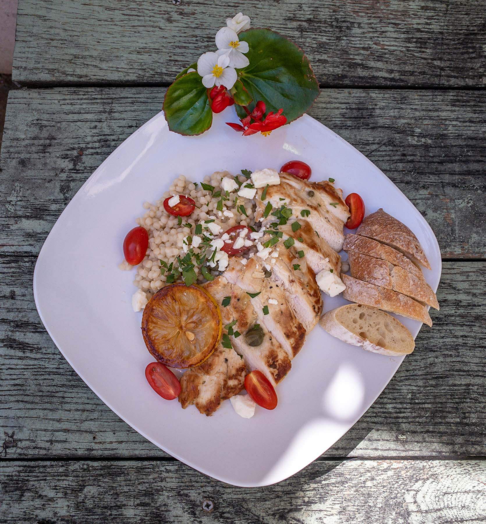 The delectable Greek Chicken is served over pearl couscous and garnished with feta cheese. Greek chicken from Farm and Fig Catering
