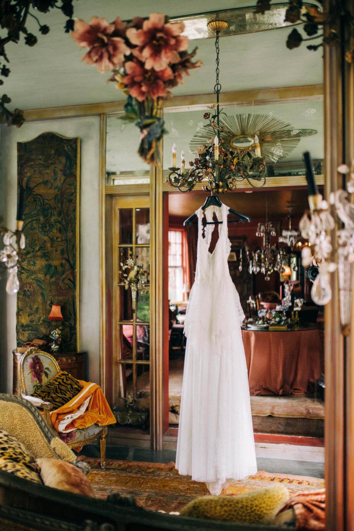 "My mom loves fabrics and antique lace, and I think that's been imprinted on me," Allison says of the dress she was drawn to. "The vibe of the house is so ethereal and 'magical garden,' so I really wanted a boho, timeless dress. When I saw this one on eBay, I was obsessed. It was perfect. I felt like it was age-appropriate but sexy and simple." Wedding dress hanging in room with eclectic antiques
