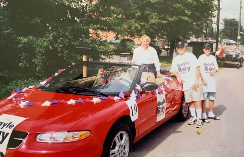 Gayle in red car with Gayle Ray re-election signs