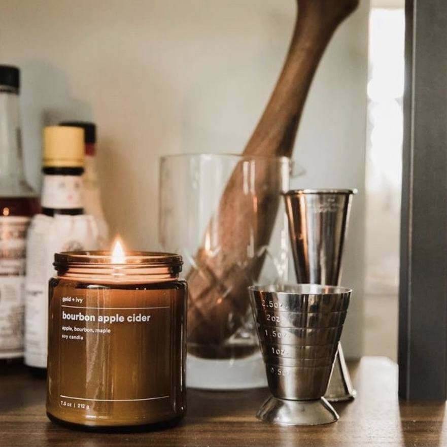 gold + ivy "bourbon apple cider" candle, $28, here | Image: gold + ivy SB Shop holiday gifts: bourbon apple cider candle on a bar