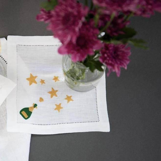 Lettermade "Champagne & Stars" linen cocktail napkin set, $48, here | Image: Lettermade Linen napkin with champagne and stars embroidered