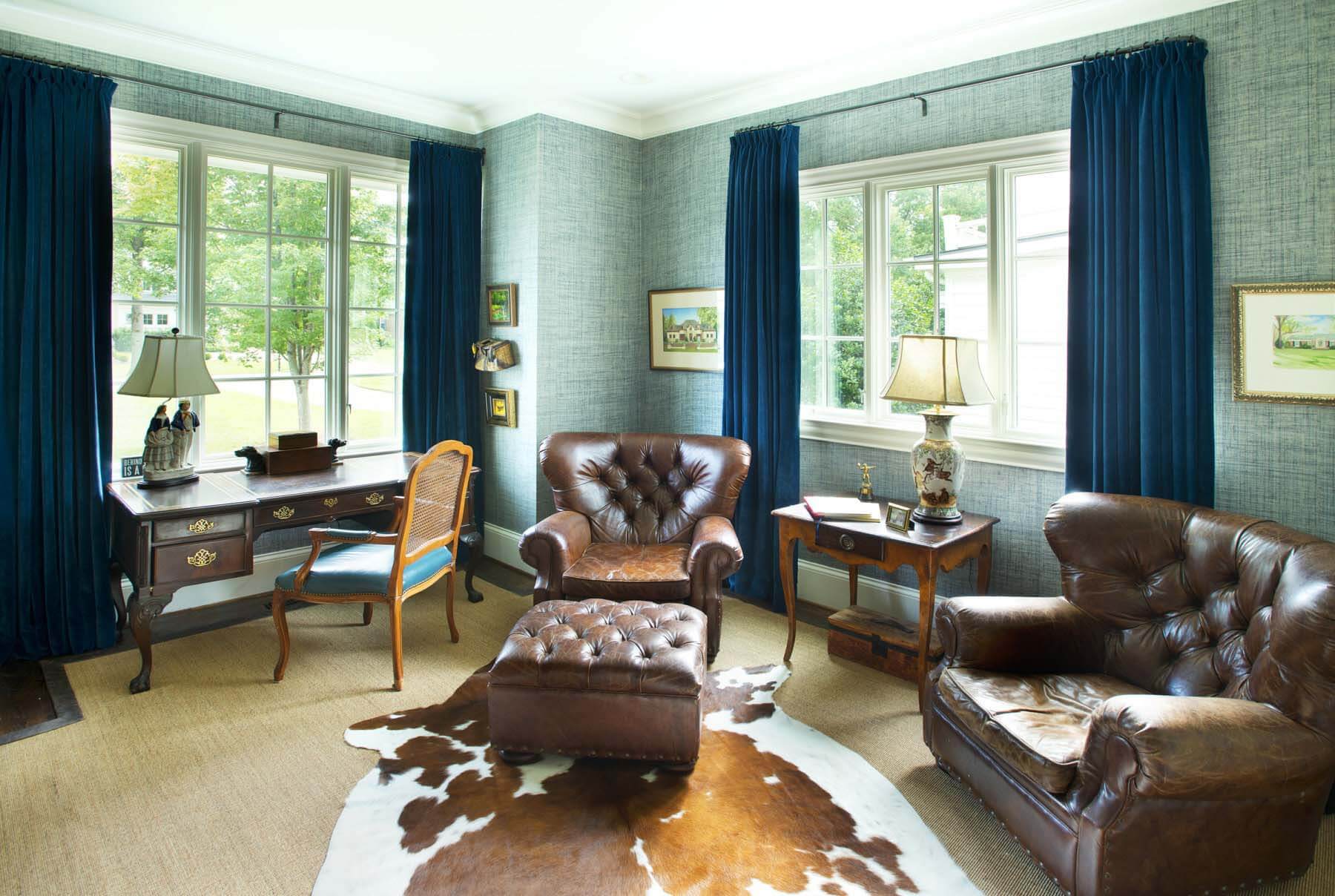 A beautiful home office with grasscloth walls, comfy leather furniture and an animal hide rug.