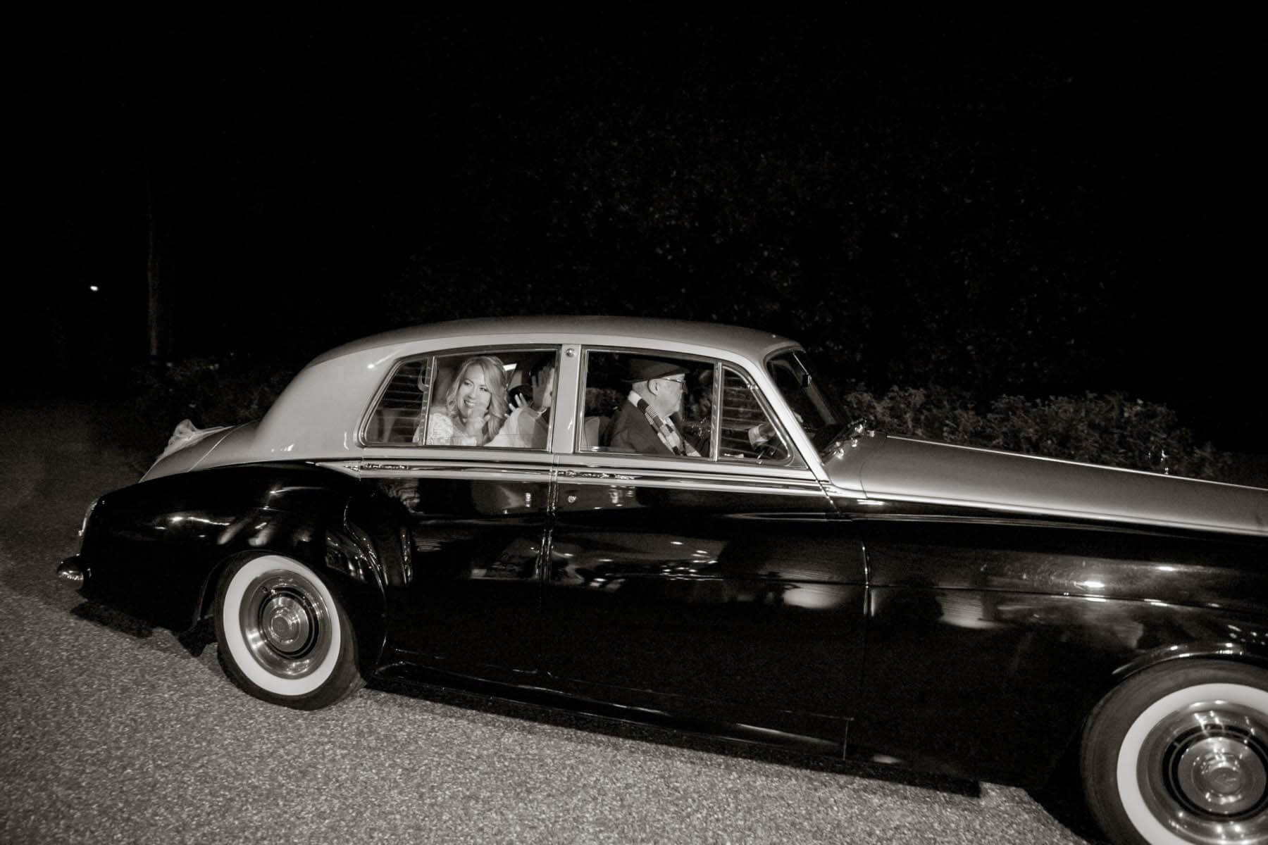 A classic departure, the newlyweds left their reception in a Rolls Royce, complete with a fully-suited driver. Talk about leaving in style! Before dropping them off, the driver took them for a spin down Broadway — the couple felt like royalty. "People were screaming at us like we were famous," says the bride. The bride and groom leave their wedding in a classic car