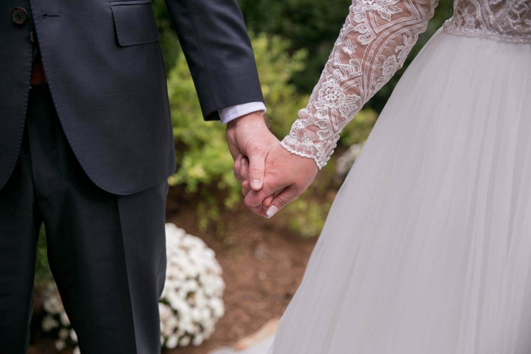In a beautiful tribute to her father, who passed away seven years ago, Sarah's mom cut out a heart-shaped patch from her own wedding dress, which Sarah then had sewn into hers so she could carry his memory down the aisle. Close-up of bride and groom holding hands