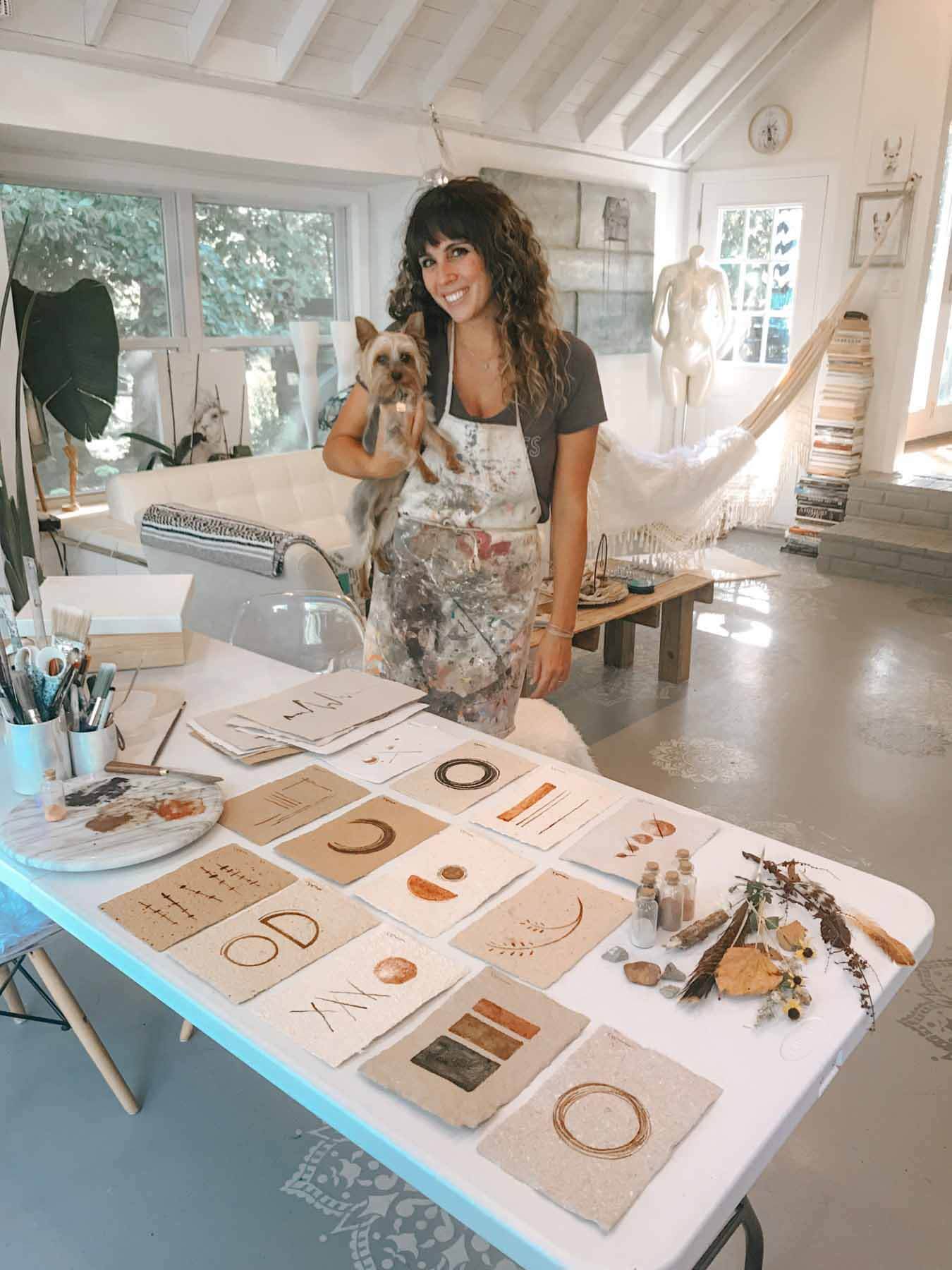 Artist Kristin Llamas in her home studio with dog, Poet.
