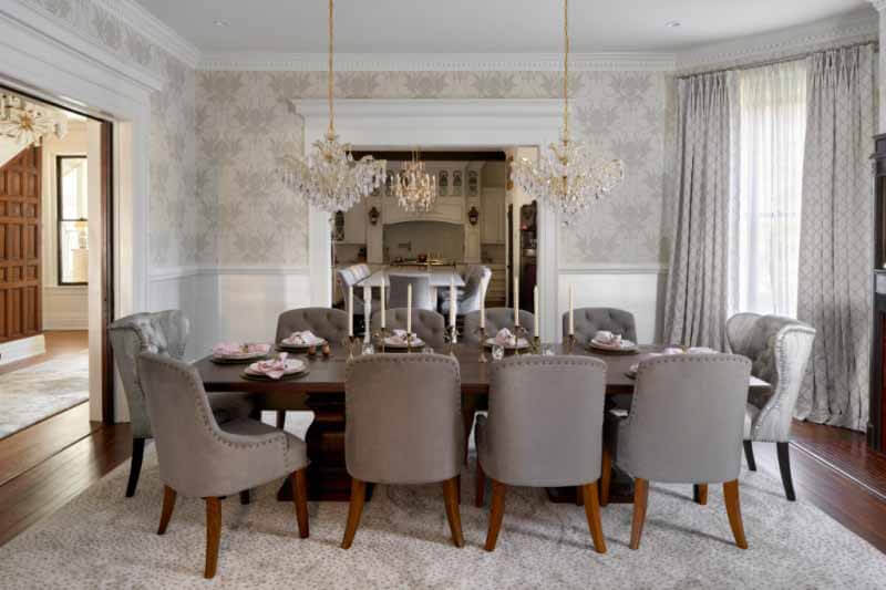 post-renovation dining room with dual chandelier and silver dining chairs