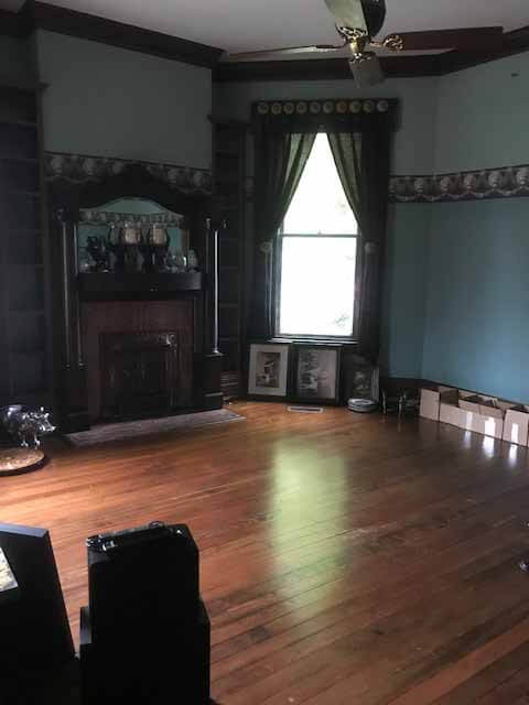 Pre-renovation photo of the library, with wood floor and dated blue wallpaper