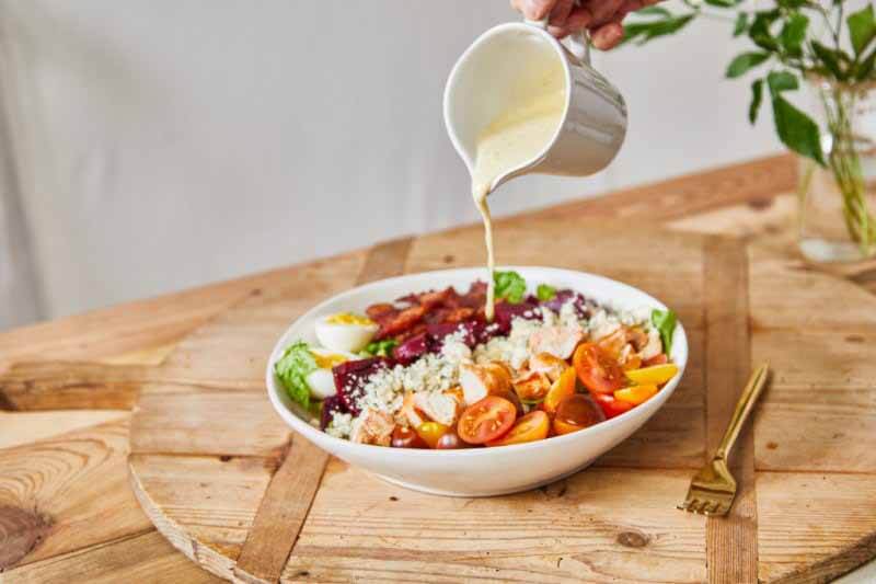 Greenery Co. salad with dressing being poured in