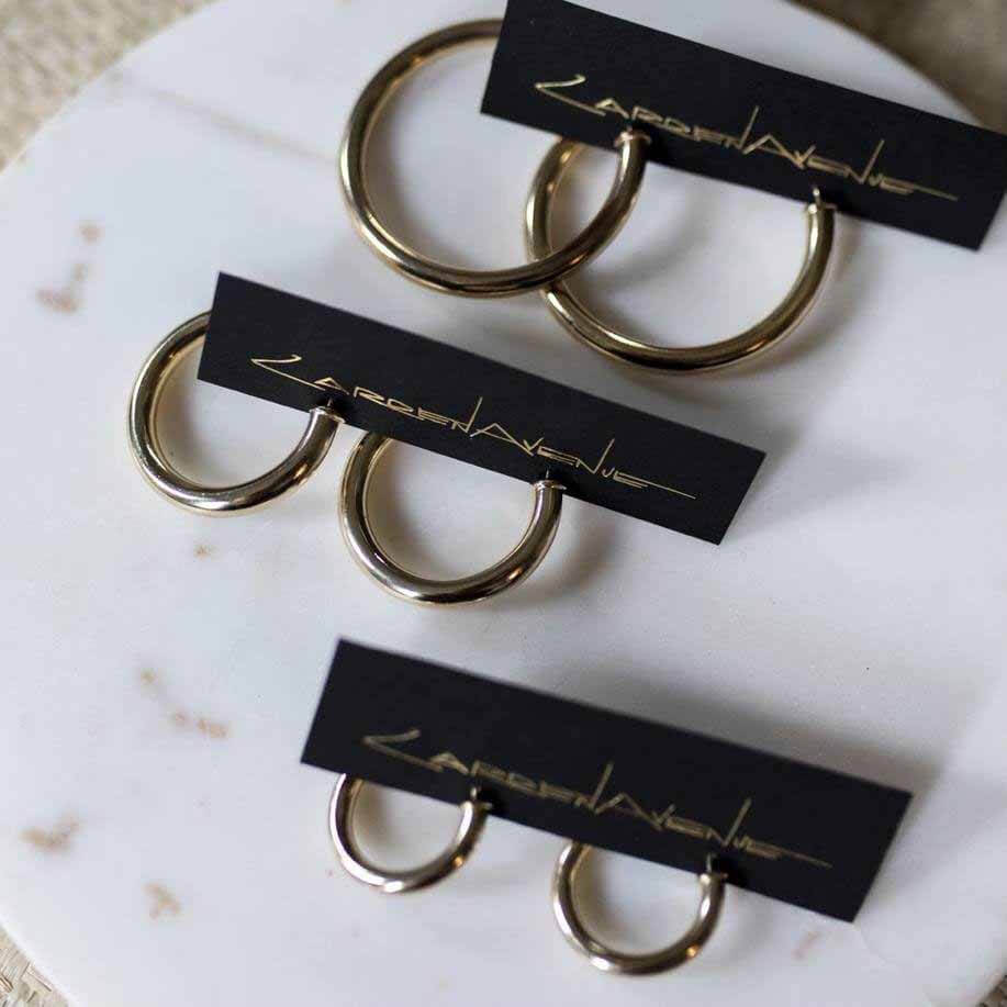 Shop the Carden Avenue "Mila" hoops for $98 to $128 HERE. Image: Caroline Sharpnack Three different sized chunky gold hoops on white table