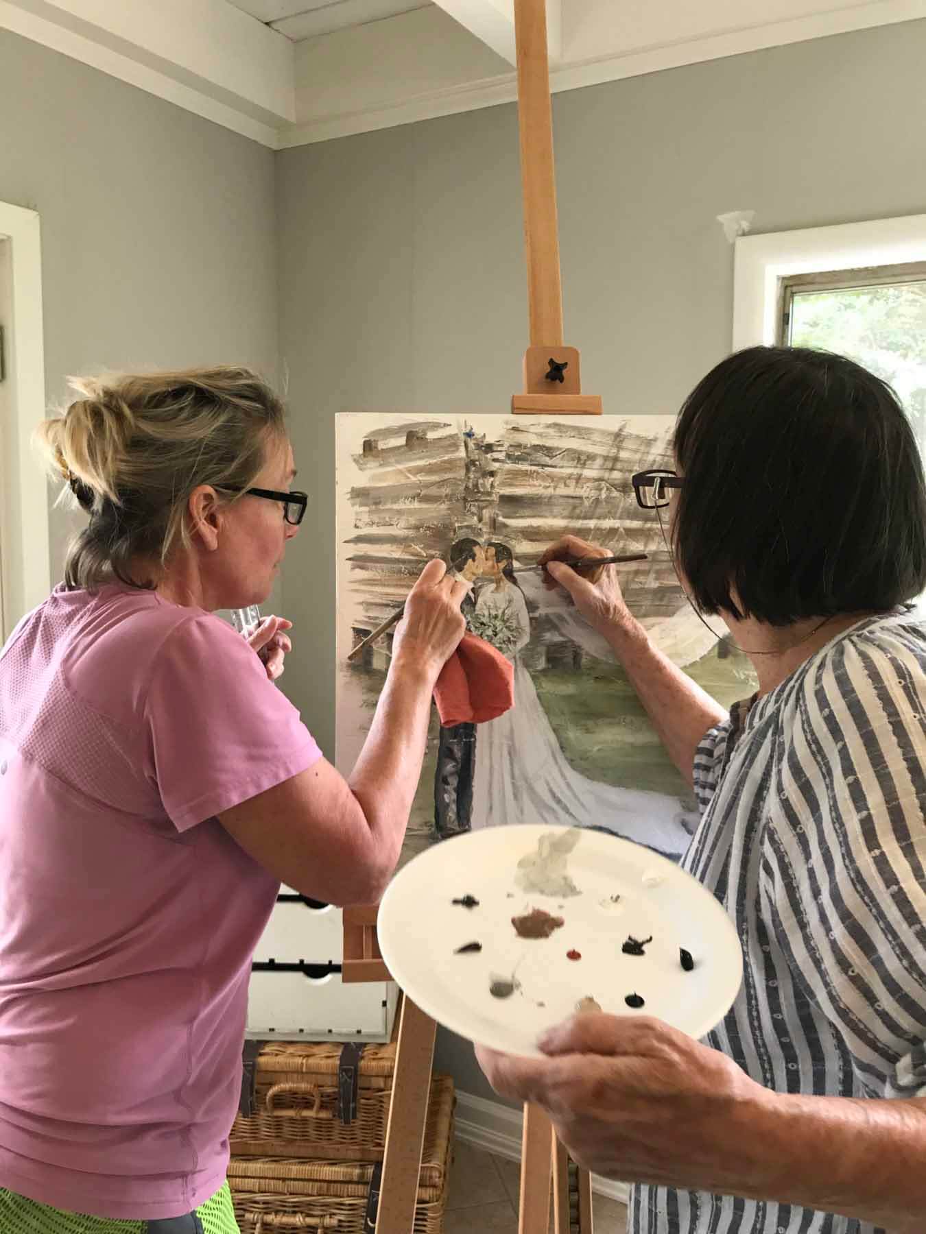 Georgia and Mama Jane entered the art world by painting and selling furniture, which eventually led to their one-of-a-kind canvas paintings. Here, the two work together on a custom bridal painting. Georgia and Jane painting bride and groom