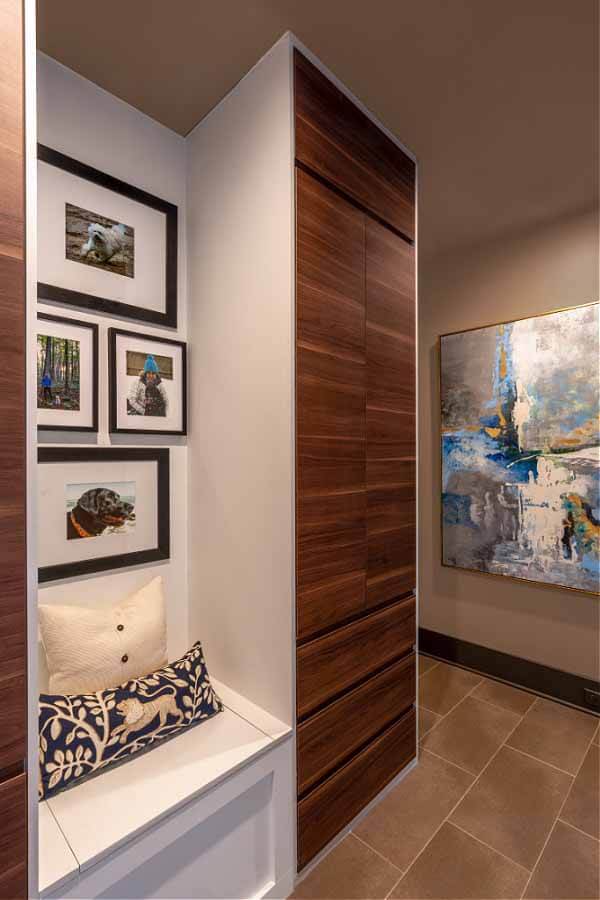 Walnut veneer and white lacquer-sided IKEA cabinetry bookends this sweet little mudroom reading nook that displays photos of the homeowners' beloved pups. A reading nook in the mudroom