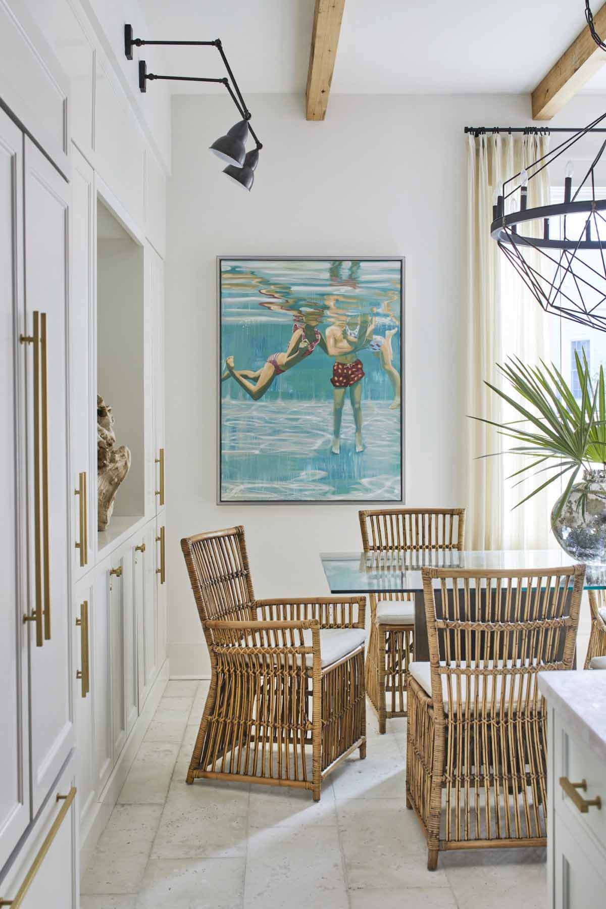 The artwork that hangs in the dining area is a painting of Ashley's kids by Sarah Soule Webb. To the left, a large piece of wood acts as art, and doors to the back bedroom are hidden behind cabinet fronts that match those used in the kitchen and dining area for a discrete look. Dining room with Sarah Soule artwork
