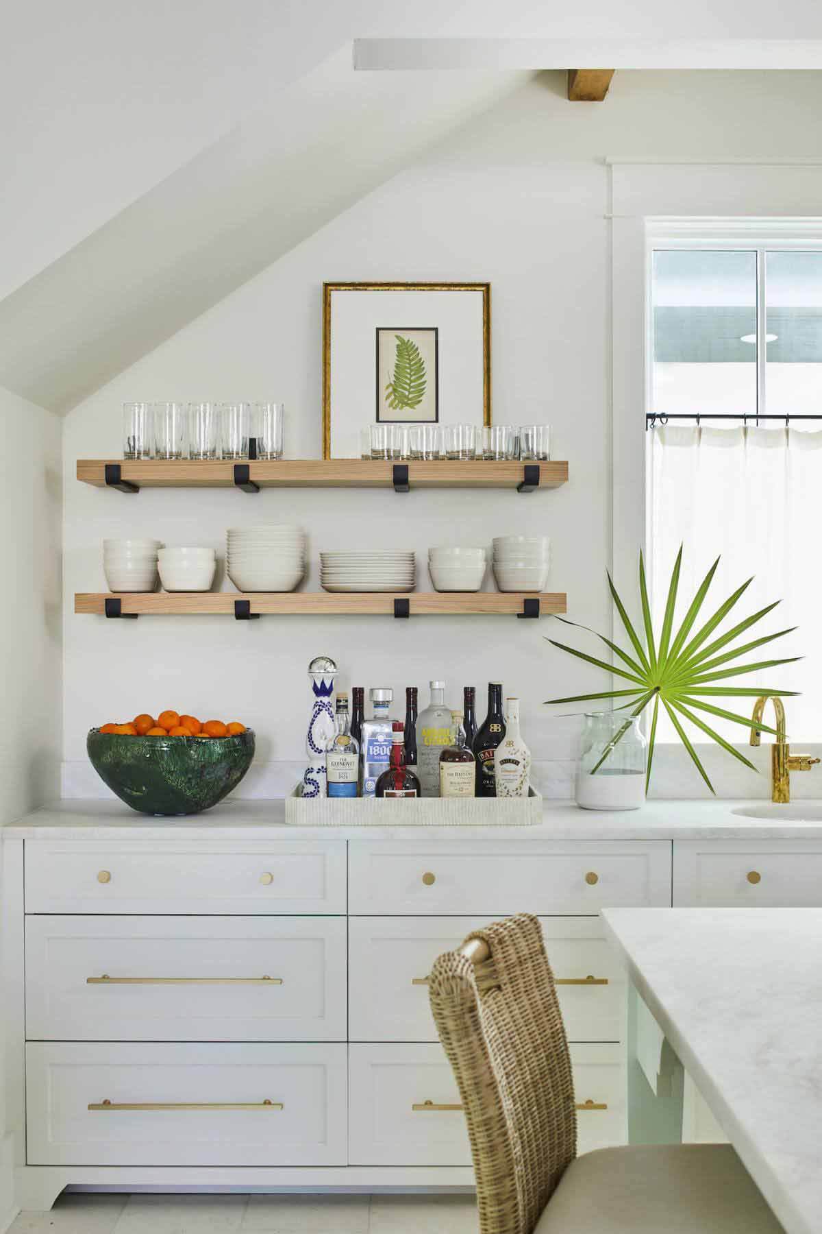 The left side of the kitchen was designed to offer overflow storage, plus a place for a bar. The space was previously a powder bathroom that opened under the stairs. Kitchen storage and bar in Florida house