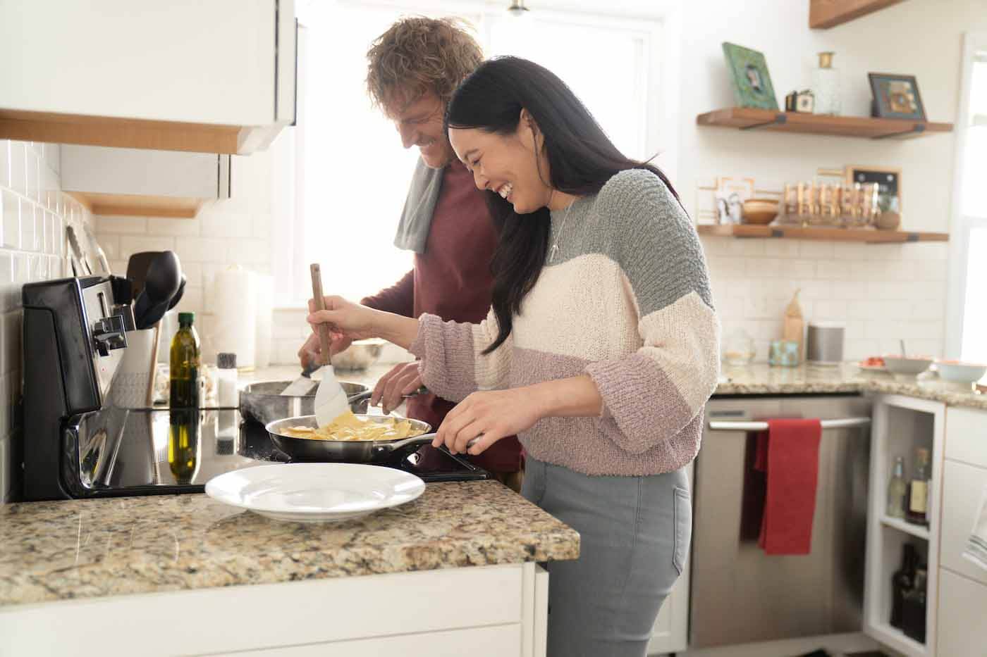 Couple laughing and cooking in kitchen