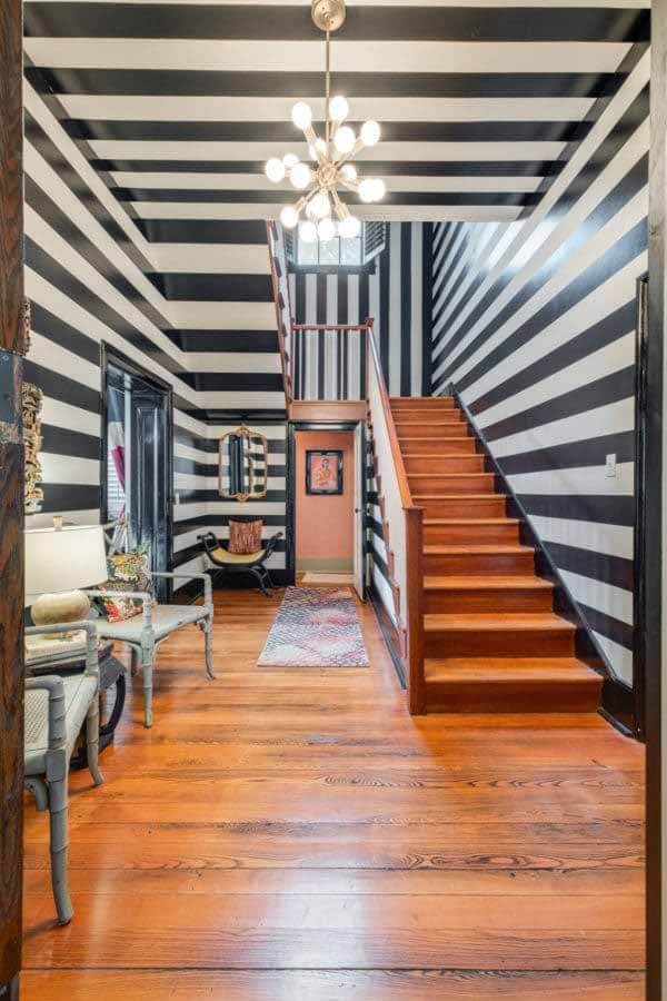 Straight out of a David Lynch film, black-and-white-striped walls offer an optical illusion in this space that Therese fondly refers to as the "Beetlejuice Hallway." Image: Zach Harrison Photography Black and white striped walls in a hallway at the Shute-Turner House
