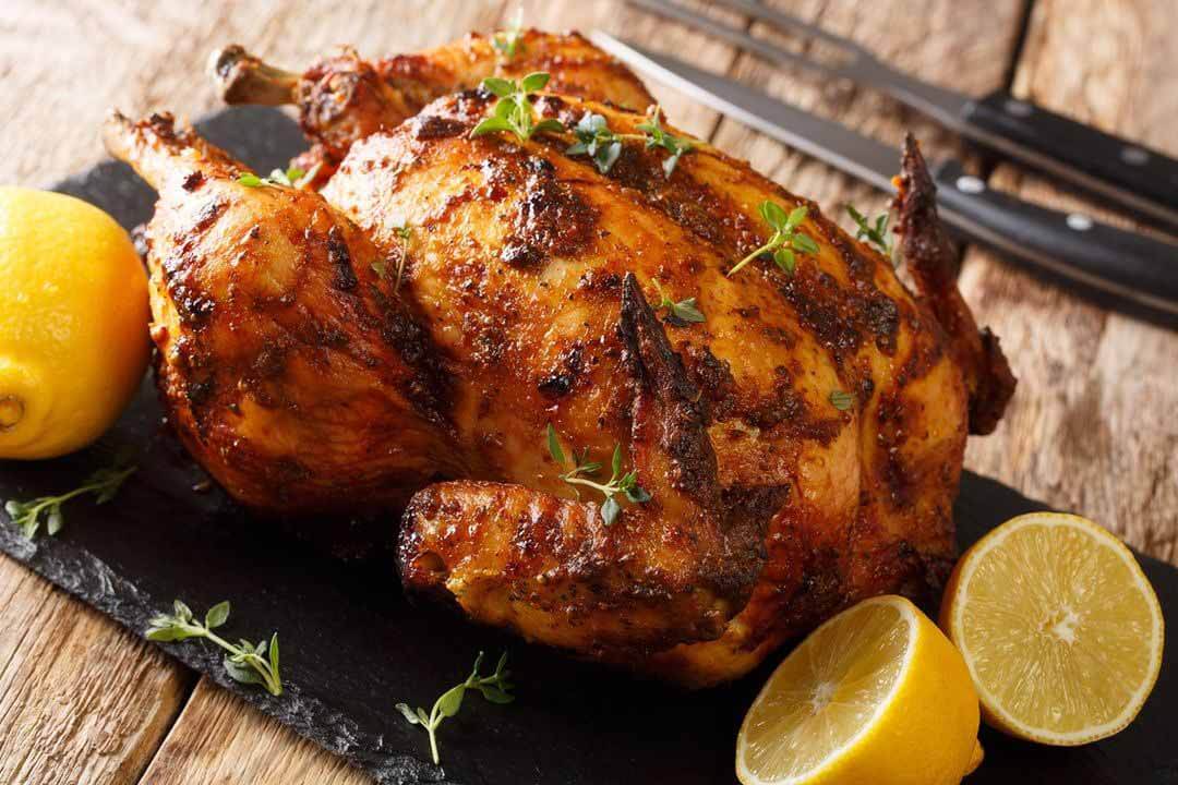 Rotisserie chicken on a slate board with lemons