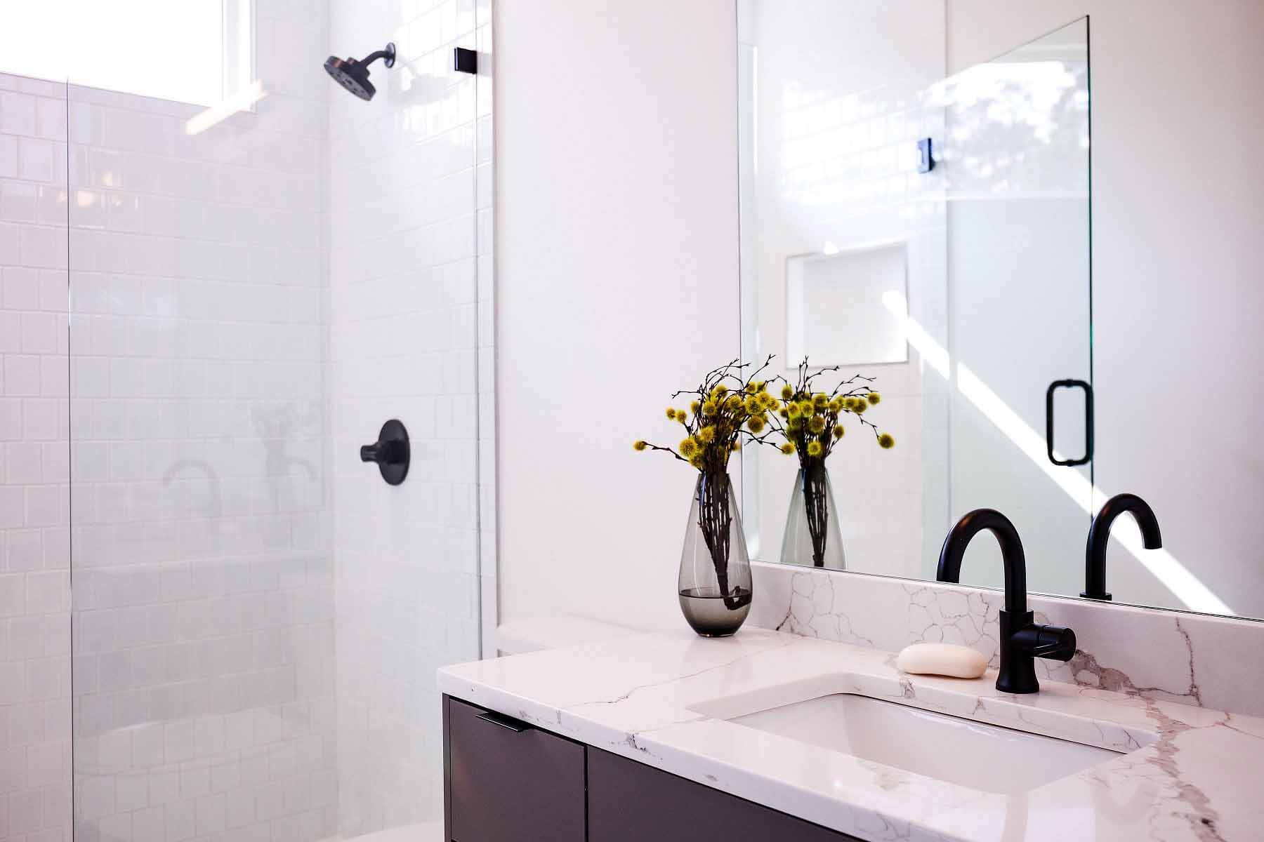 White bathroom with white marble counters and brass faucet