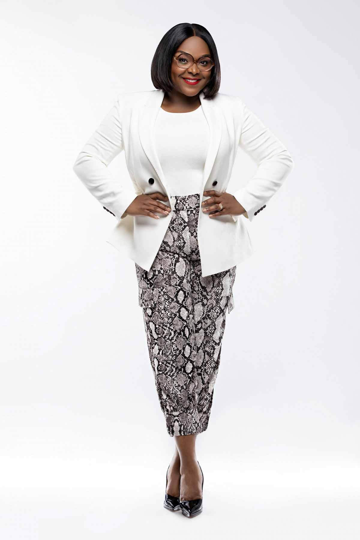 Brittany Cole standing with her hands on her hips, wearing a white blazer