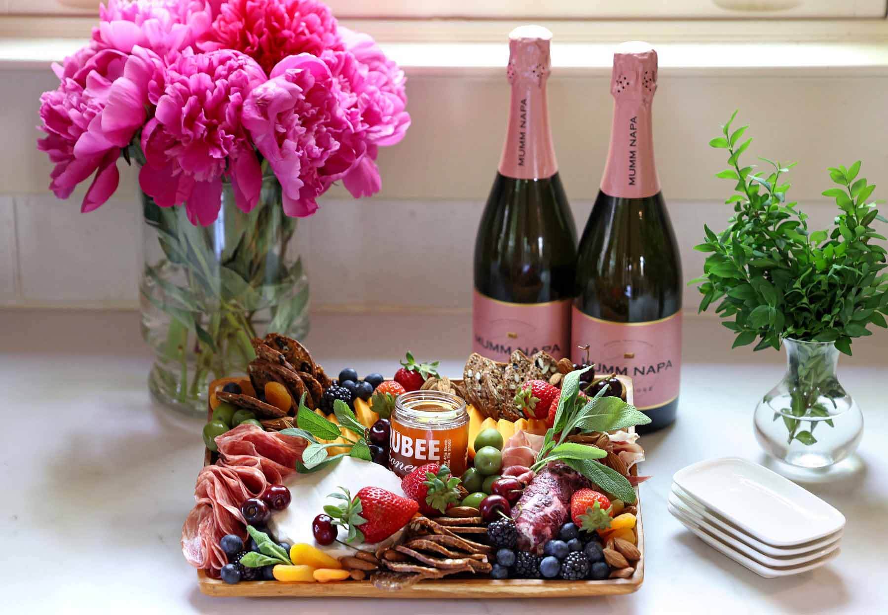 Charcuterie spread placed next to flowers and bottles of wine