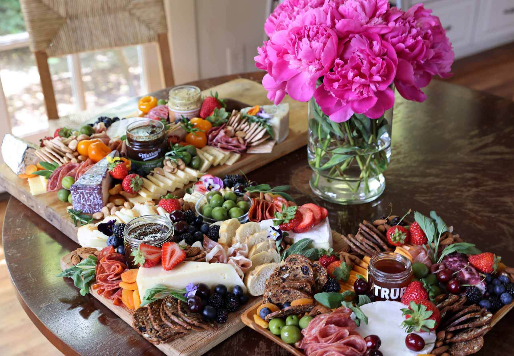 Three charcuterie boards next to fresh-cut flowers