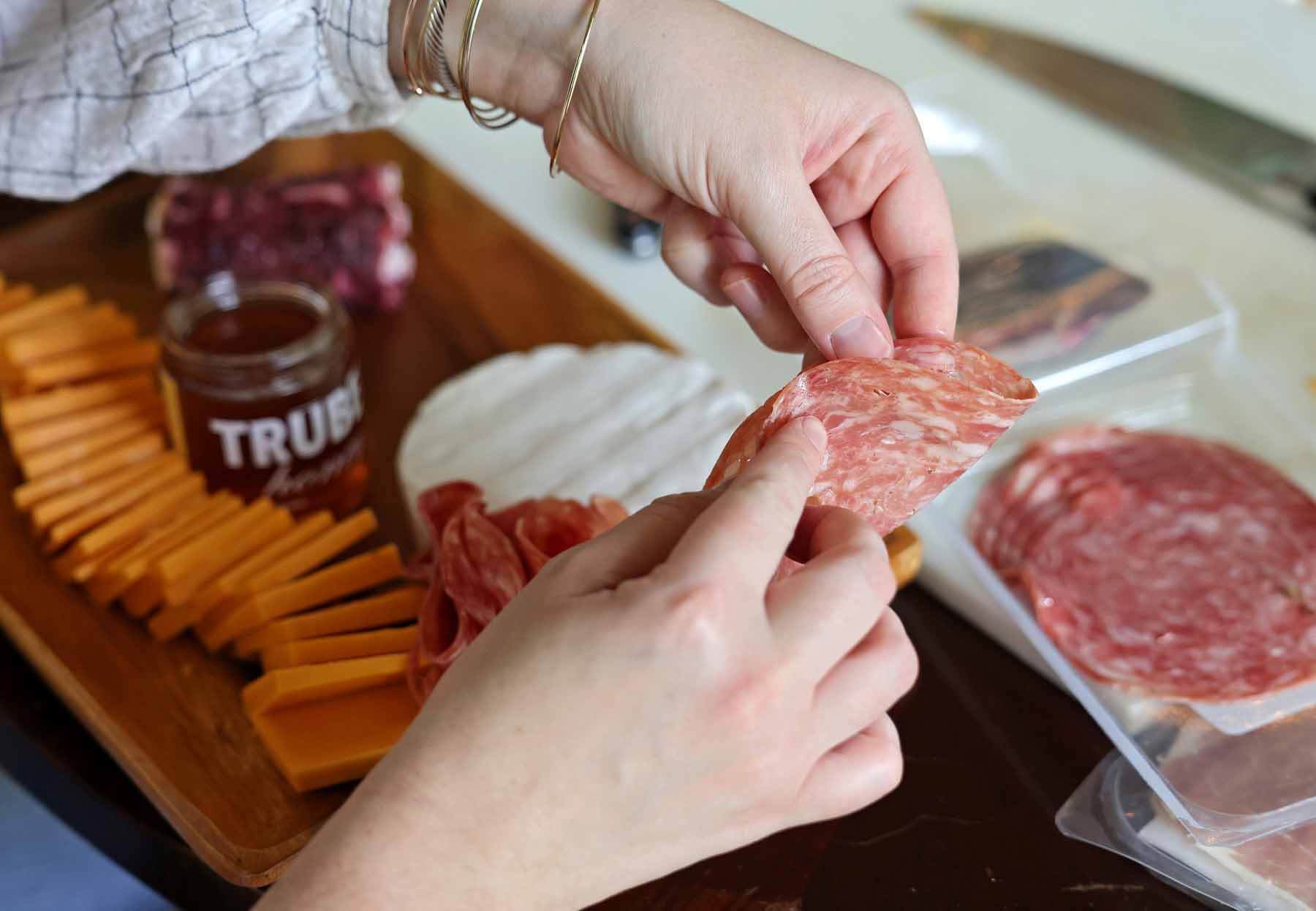 Cortney folding a piece of salami to make a flower shape